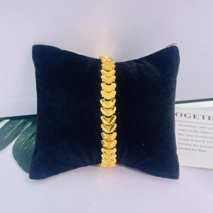 Bracelet chaîne cœur plaqué or 24K en gros plan sur un coussin en velours noir