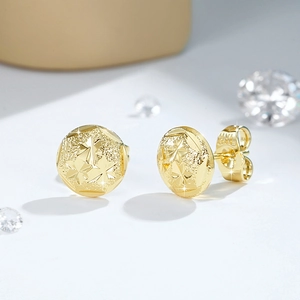 Dettaglio macro di orecchini tondi in oro 14K con finitura opaca e stelle