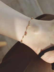 Detail eines eleganten Gold-Fußkettchens mit polierten Kugeln an einer feinen Kette