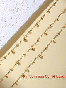 Detaillierte Nahaufnahme der goldenen Perlen-Fußkette auf minimalistischem Stein