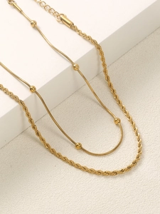Detail of gold double-layered anklet featuring a bead snake chain and twist rope design