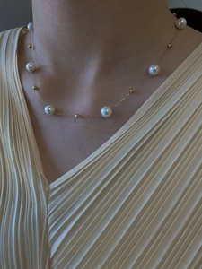Nahaufnahme einer minimalistischen Perlenkette mit Goldperlen am Hals eines Models