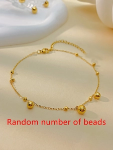 Detailaufnahme einer goldenen Perlen-Fußkette mit Karabinerverschluss und Kette