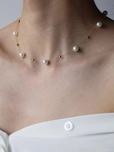 Makroaufnahme von weißen Perlen und Goldperlen an einer zarten Halskette für Damen