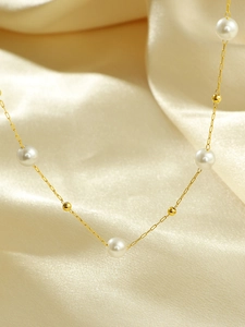 Detail der eleganten Goldperlenkette mit weißen Perlen auf Seidenstoff