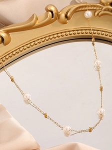 Detail einer eleganten goldenen Doppelkette mit weißen Perlen auf einem Vintage-Spiegel