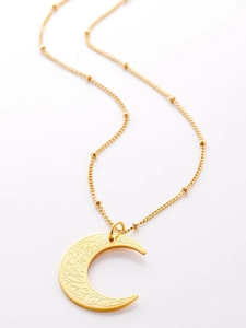 Detailopname van gouden halve maan hanger met Arabische kalligrafie en subtiele parelketting