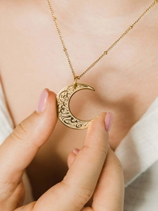 Detail van de gouden halve maan hanger met Arabische kalligrafie aan een kralenketting