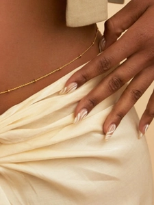 Detailed macro view of a gold hollow beaded belly chain on female waist with silk fabric