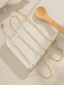 Close-up of golden beaded satellite chain with lobster clasp on a ceramic tray