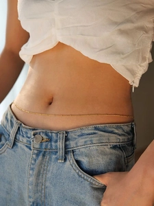 Detail of a thin gold beaded waist chain worn by a woman for beach fashion accessory