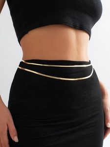 Detail of double-layer gold snake chain waist belt on black fabric background