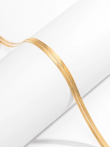 Detail of double-layer gold stainless steel herringbone snake chains on white column
