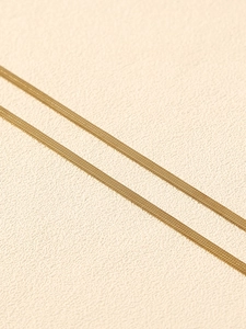 Detailed close-up of golden flat snake bone chain with smooth scale texture