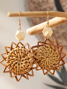 Macro shot of Bohemian handmade woven rattan drop earrings with yellow wood bead detail