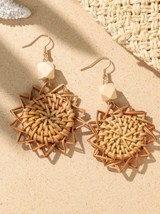 Detailed macro shot of bohemian woven straw earrings on beach sand with summer vibes