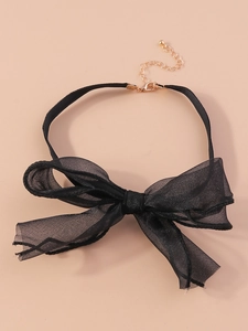 Detail eines schwarzen Chokers mit Netzschleife, goldener Kette und Karabinerverschluss
