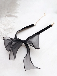 Detail von schwarzem Samt-Choker mit großer Organza-Schleife und goldener Kette