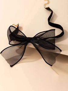 Nahaufnahme von schwarzem Mesh-Schleifen-Choker mit goldenem Verschluss für Partys