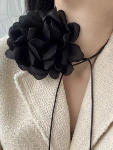 Detail of oversized black fabric flower choker with long ribbon ties for party wear