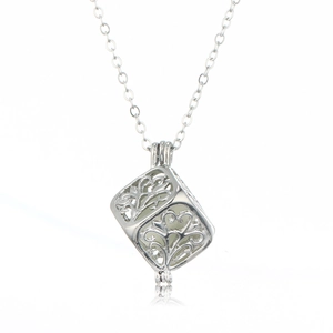 Close-up of a silver hollow cube pendant featuring a glowing bead and Tree of Life patterns