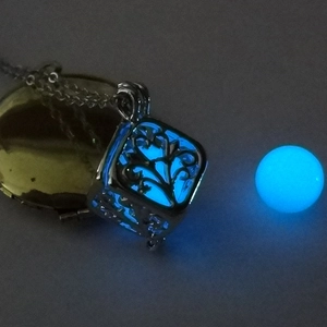 Close-up of hollow square tree of life pendant with glowing blue luminous bead inside