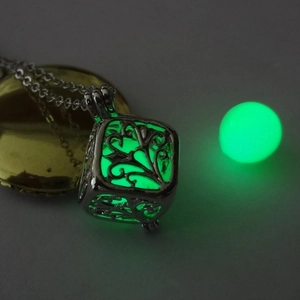 Close-up of a hollow tree of life cube pendant with green glowing luminous bead