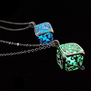 Detail of hollow tree of life cube pendant with glowing blue and green luminous beads