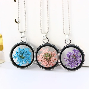 Dettaglio macro di ciondoli d'argento fatti a mano con veri fiori secchi blu rosa viola