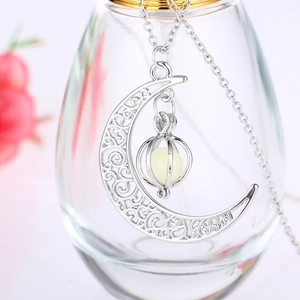 Detailed view of silver hollow moon pendant with luminous bead on a cross chain