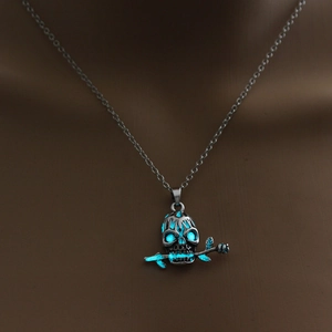 Macro view of gothic skull necklace pendant with glowing blue eyes and a rose stem
