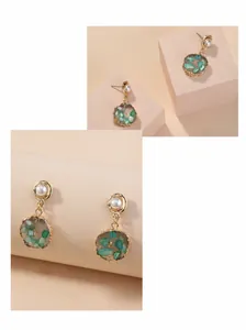 Detail van vintage gouden oorknopjes met groene edelstenen en witte imitatieparels
