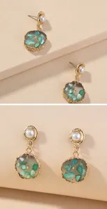 Detail van vintage oorbellen met groene stenen, goudfolie en witte faux-parels