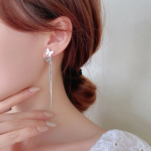 Detail of silver butterfly tassel earrings with rhinestones on a female model