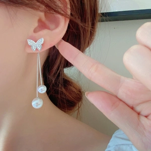 Detail of long butterfly tassel earrings with sparkling crystals and elegant white pearls