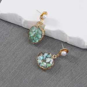 Vintage oorbellen met groene imitatiesteen, gouden rand en witte parels op een steen