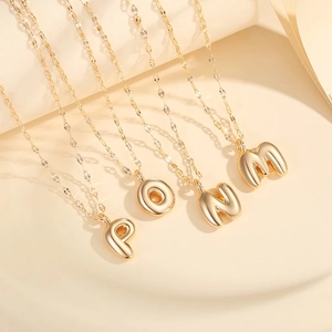 Golden balloon initial pendant necklace with polished P O N M bubble letters on a link chain