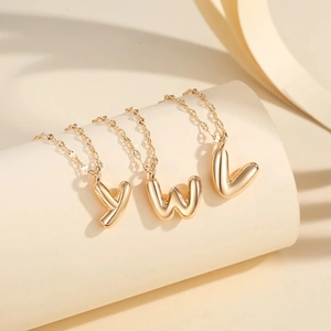 Detail shot of 3D balloon style letter pendants in gold finish on minimalist chains