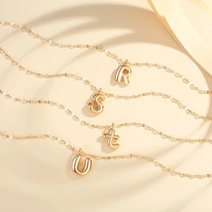 Detail view of 3D bubble letter R S T U gold plated necklaces with minimalist chains