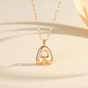 Macro shot of gold-plated bubble letter A pendant on a fine chain jewelry piece