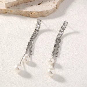 Detail of silver tassel earrings with sparkling rhinestones and delicate white pearls