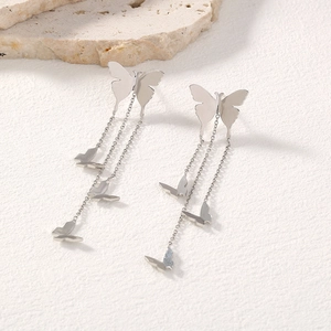 Detailed view of silver butterfly tassel earrings on a natural stone background