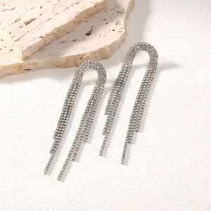 Detail of silver long tassel earrings with sparkling rhinestones on textured stone
