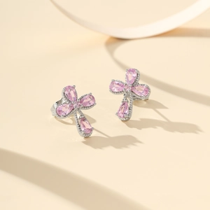 Detalle de pendientes de cruz con circonitas rosas talla pera y baño de plata fina
