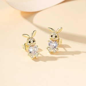 Detalle de pendientes de conejo dorado con circonita de corazón y pavé de cristal