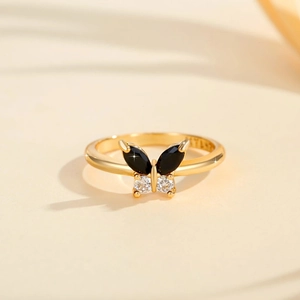 Detailansicht eines goldenen Schmetterlingsrings mit schwarzen Steinen und weißen Zirkonia