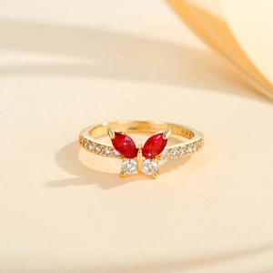 Macro view of butterfly ring featuring red marquise stones and gold pave zircon setting