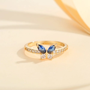 Macro shot of gold butterfly ring with blue marquise zircon and pave white stones