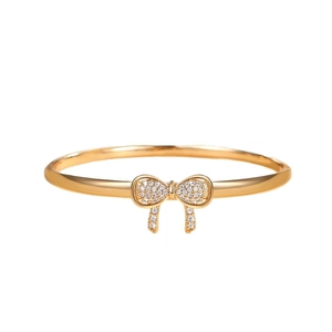 Elegant gold-plated open bangle featuring a sparkling micro-pave crystal bow centerpiece