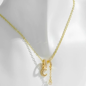 Collar chapado en oro con colgantes de luna y estrella de circón mostrado en maniquí